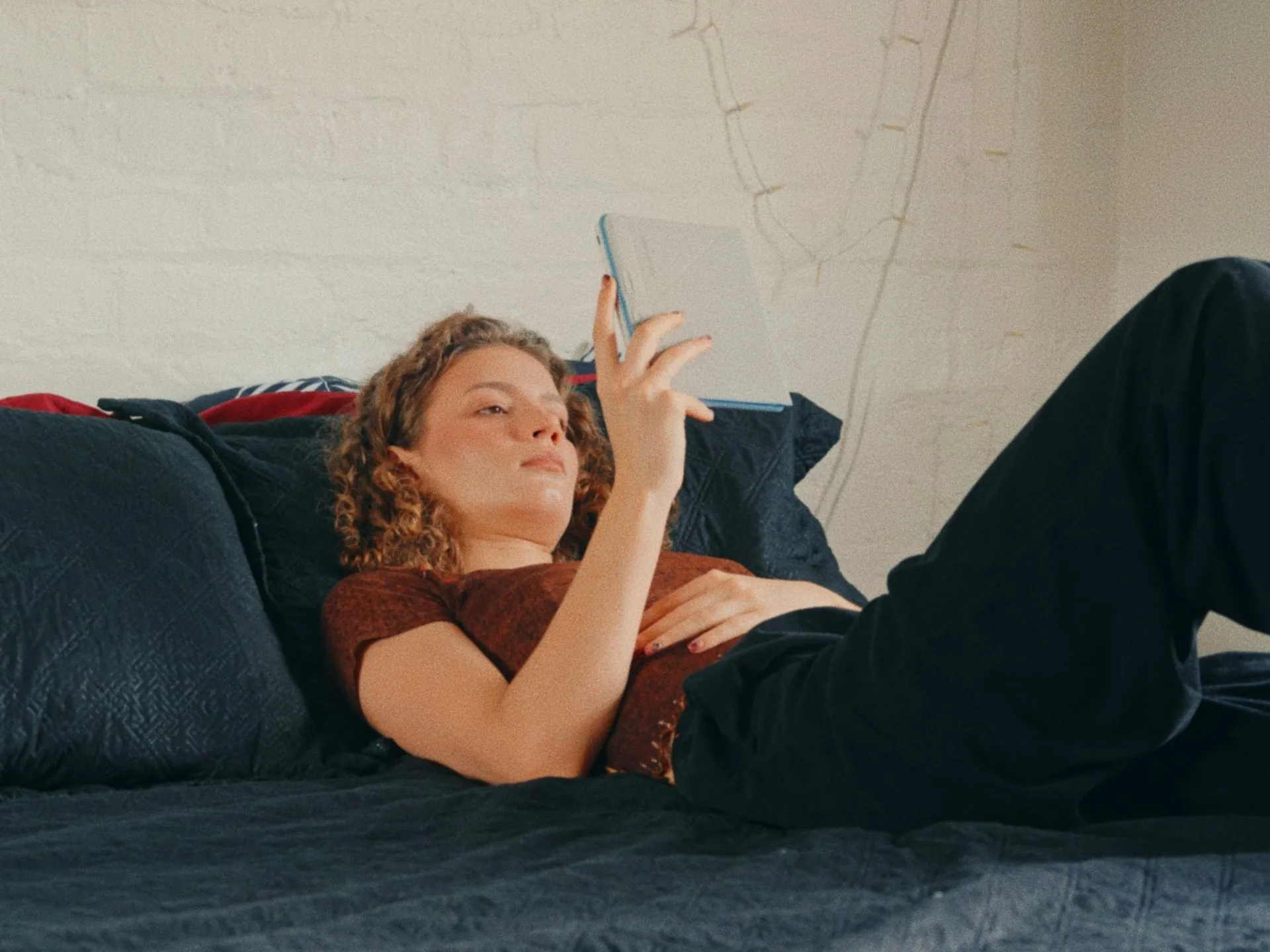 A woman reading on a Kobo e-reader in bed, from Curiouser by Studio Propel