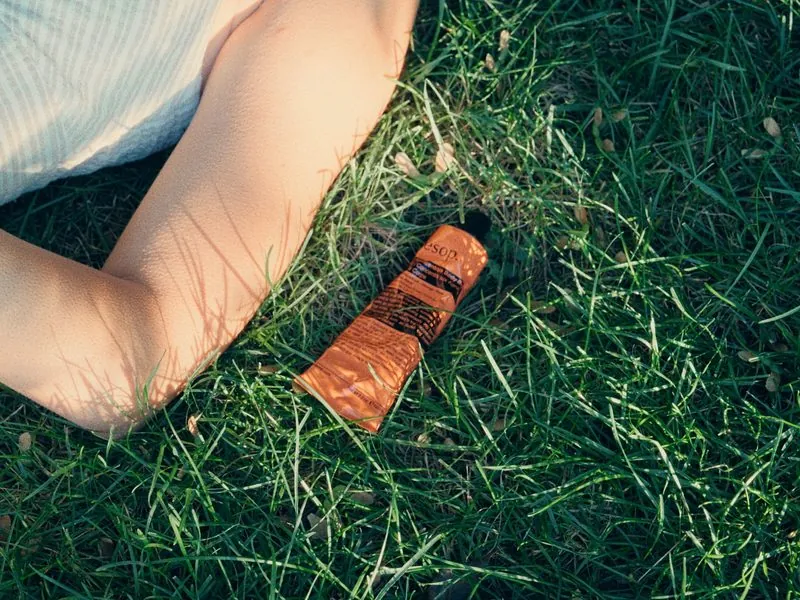 An Aesop tube in the grass beside her, from Thank You, Summer, an Aesop concept film by Studio Propel