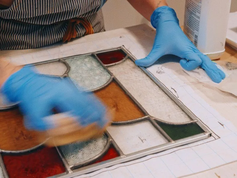 Gloved hands working over a leaded stained glass panel, from Art and Motherhood by Studio Propel