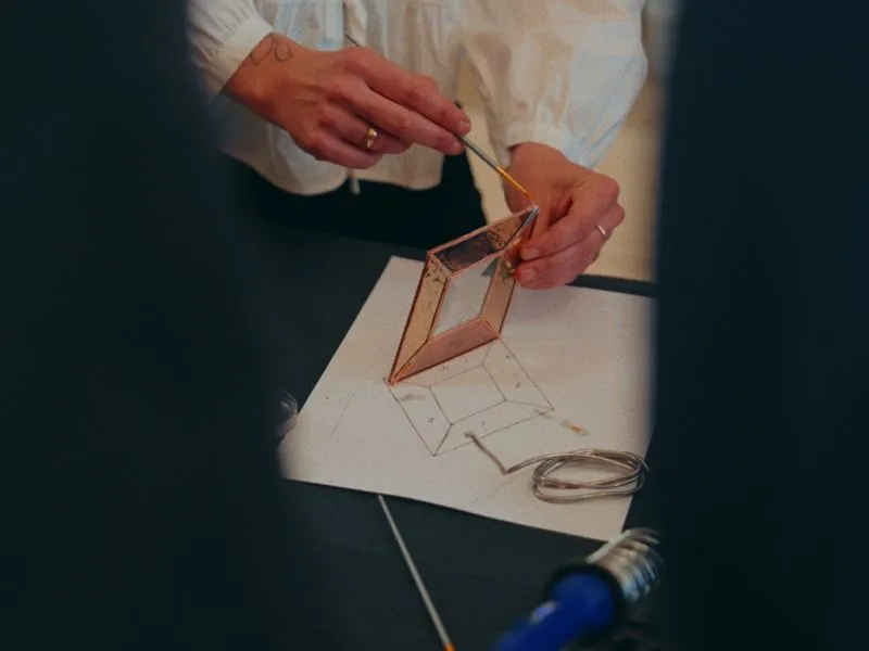Painting the edge of a copper-foiled glass piece, from Art and Motherhood by Studio Propel