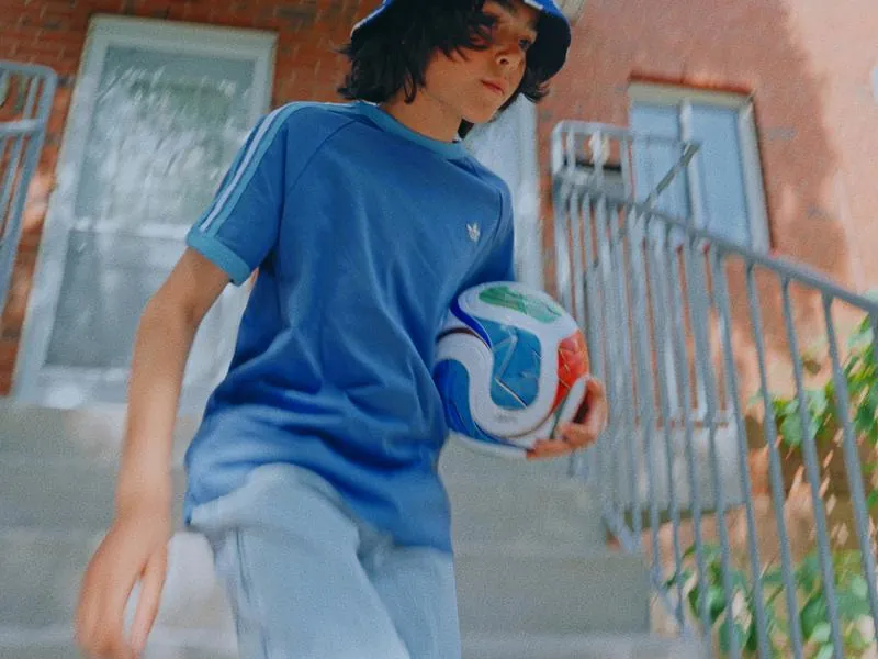 A boy walking down the front steps with a soccer ball, from Something Is Coming by Studio Propel