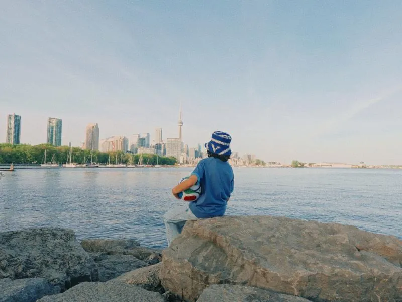 Looking out at the Toronto waterfront, ball in hand, from Something Is Coming by Studio Propel